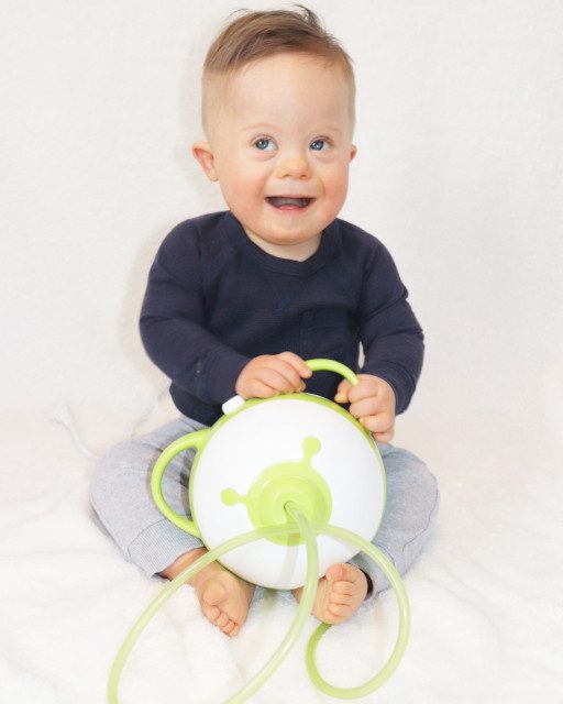 A little smiling boy holding the Nosiboo Pro Electric Nasal Aspirator in his hands