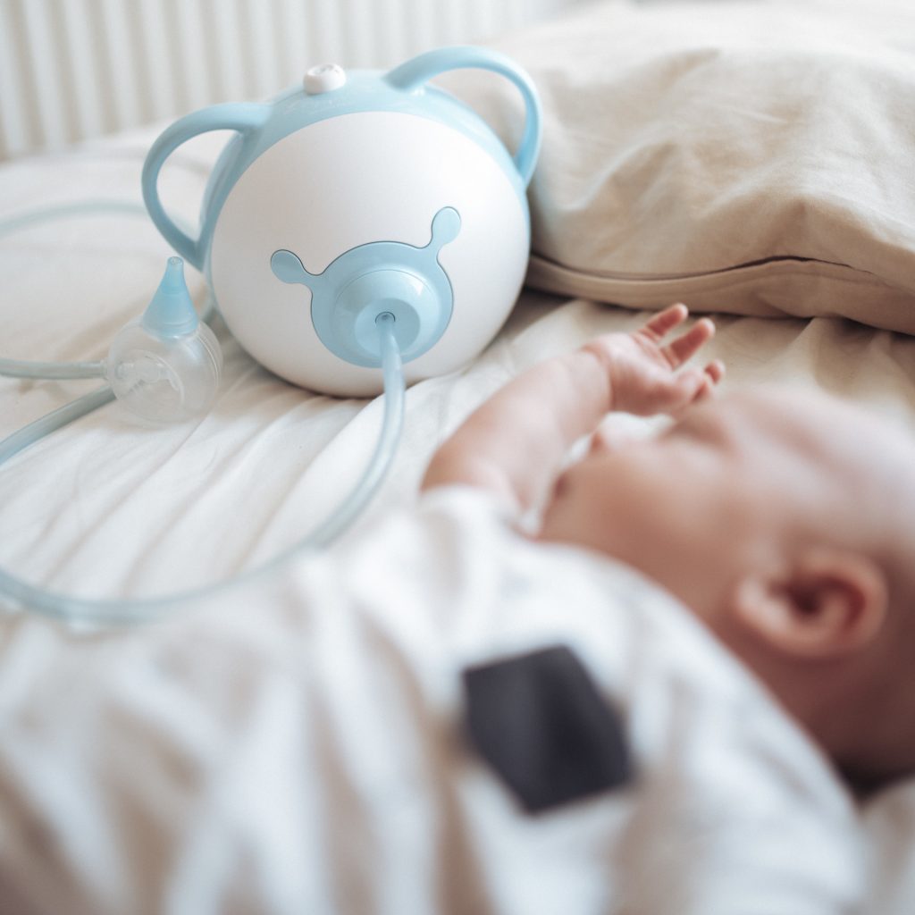 Bébé endormi à côté d'un mouche-bébé électrique Nosiboo Pro bleu