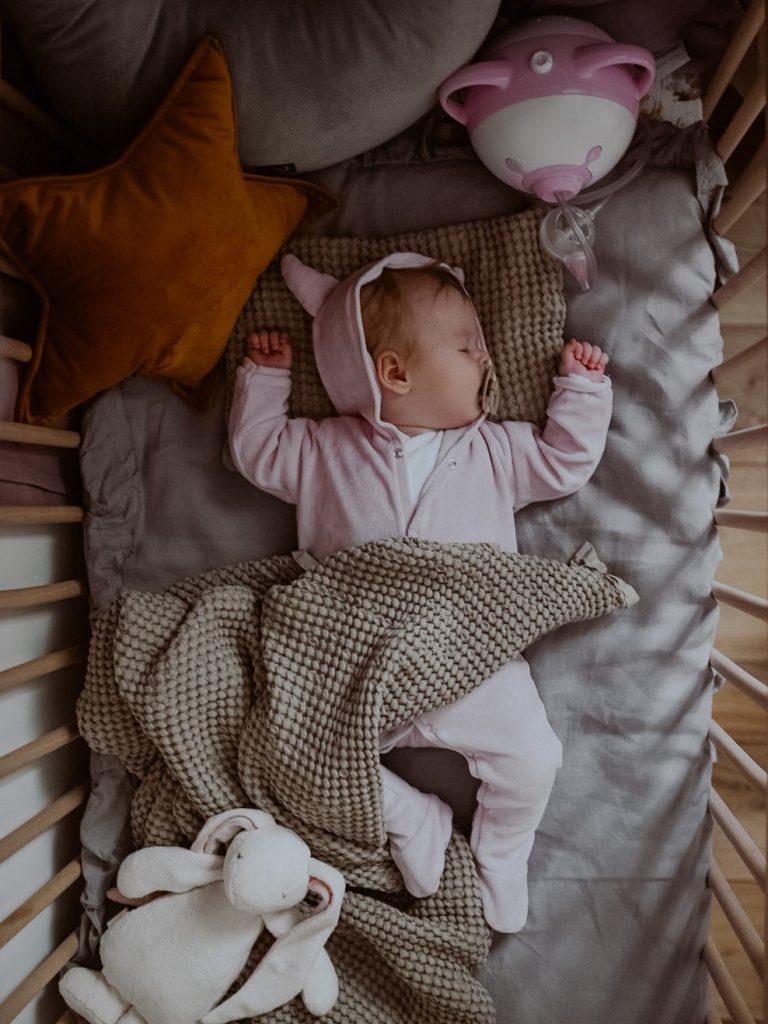 Ein kleines Mädchen schläft in einem Moses-Korb neben dem Nosiboo Pro elektrischen Baby Nasensauger