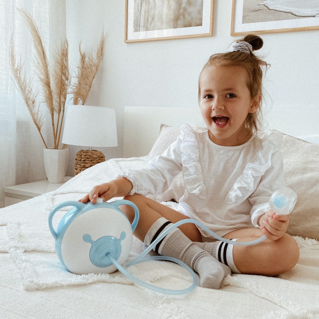 Une bambina elegante nella stanza sua con l'aspiratore nasale elettrico Nosiboo Pro