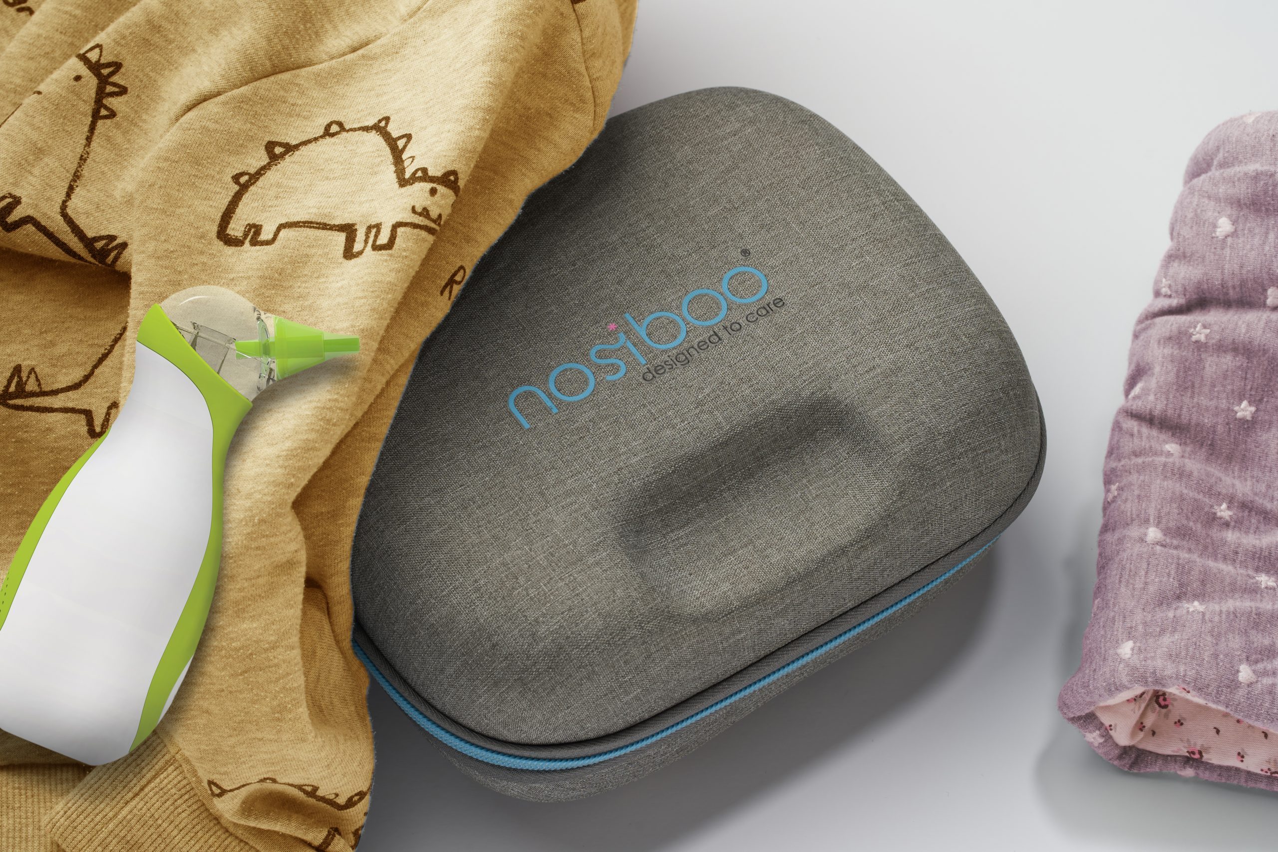 A Nosiboo Bag Go Travel Case placed on a table and covered with a cloth, with a Nosiboo Go portable nasal aspirator next to it.