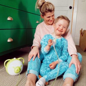 A mother with his son sitting on the floor and using the Nosiboo Pro electric nasal aspirator.