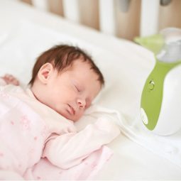 Öffnen Sie das Bild des Neugeborenen, das neben dem tragbaren Baby Nasensauger Nosiboo Go im Babybett