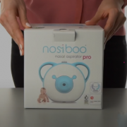 A woman holding the box of the Nosiboo Pro Electric Nasal Aspirator.