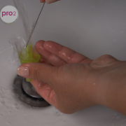 Eine Frau reinigt die Saugspitze des Nosiboo Pro2 mit einer Bürste.