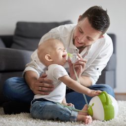Apri l'immaine di un padre chi pulisce il naso di suo figlio con l'aiuto dell'aspiratore nasale elettrico Nosiboo Pro